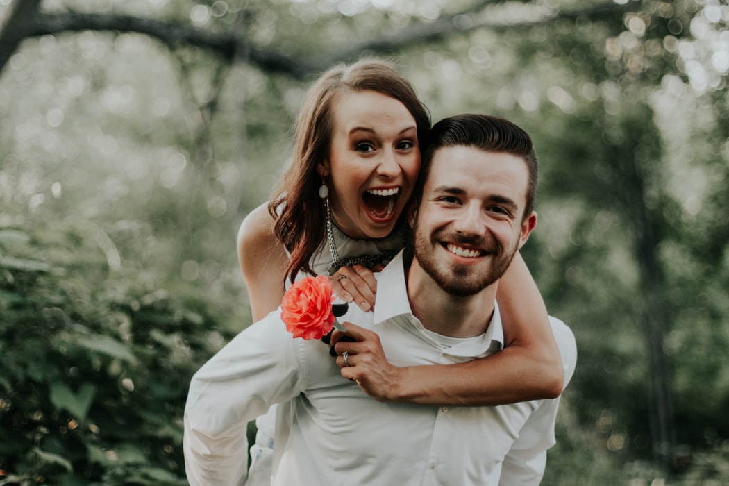 Wedding Planning - Woman Holding a Flower And Piggybacking On Man