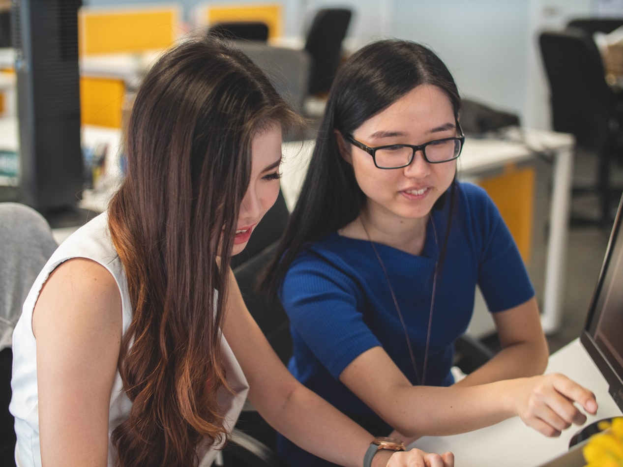 Two Brunette Women Looking At Laptop